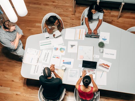 A diverse group working on marketing strategies with charts and laptops in an office setting.